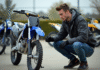 Jeune homme en gear motocross avec Yamaha 125 devant concession