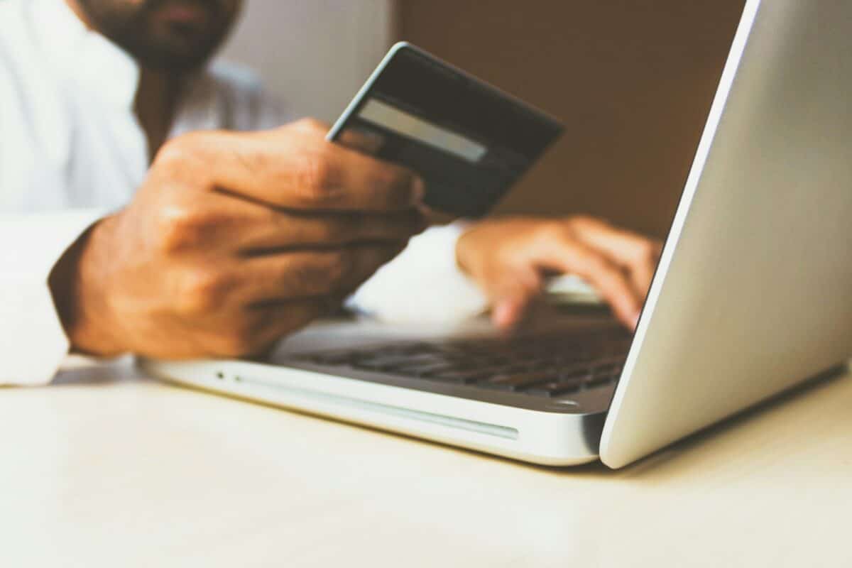 une personne avec sa carte bancaire utilisant son ordinateur